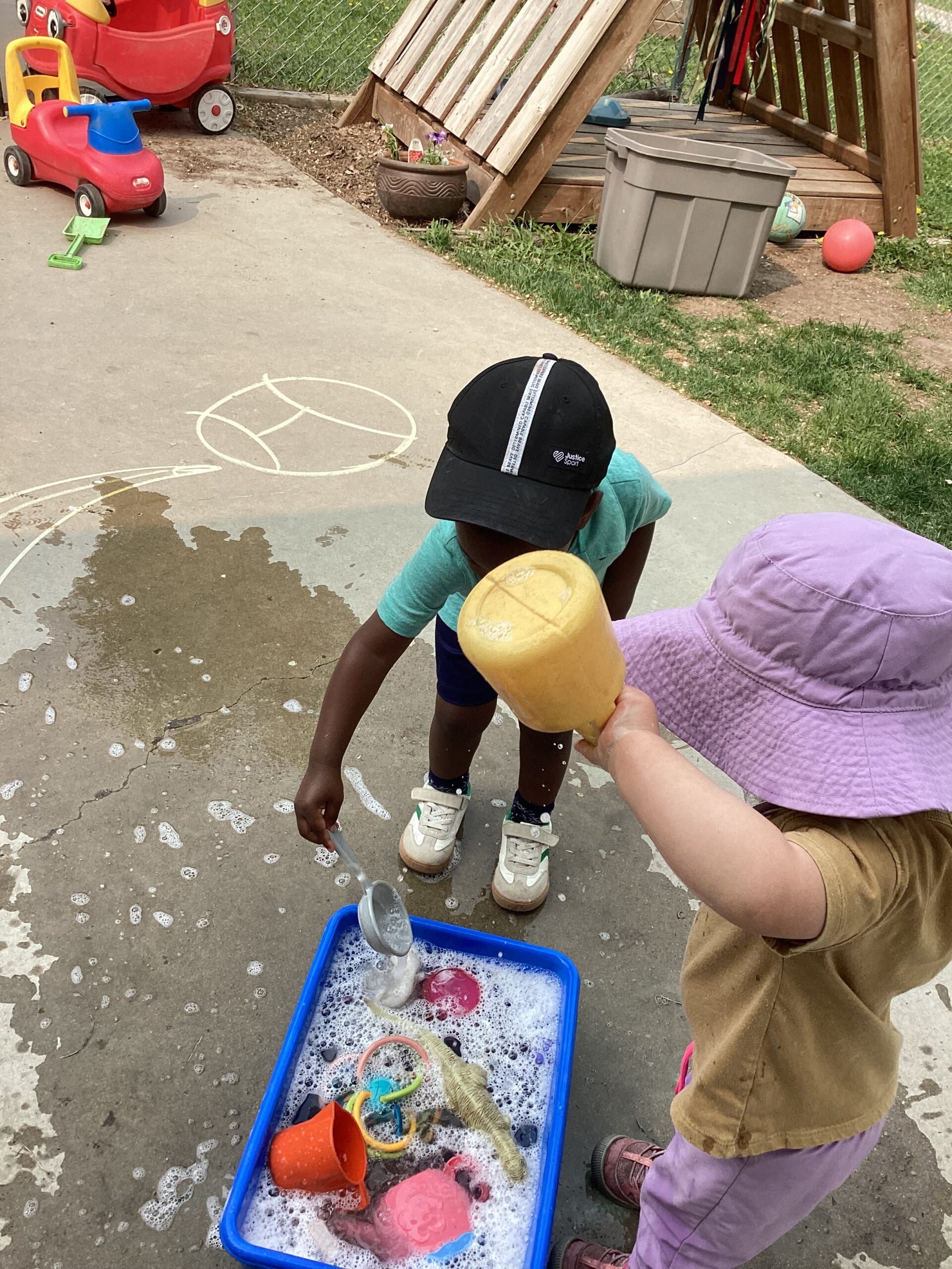 kids playing with outside toys that are in a small container filled with water