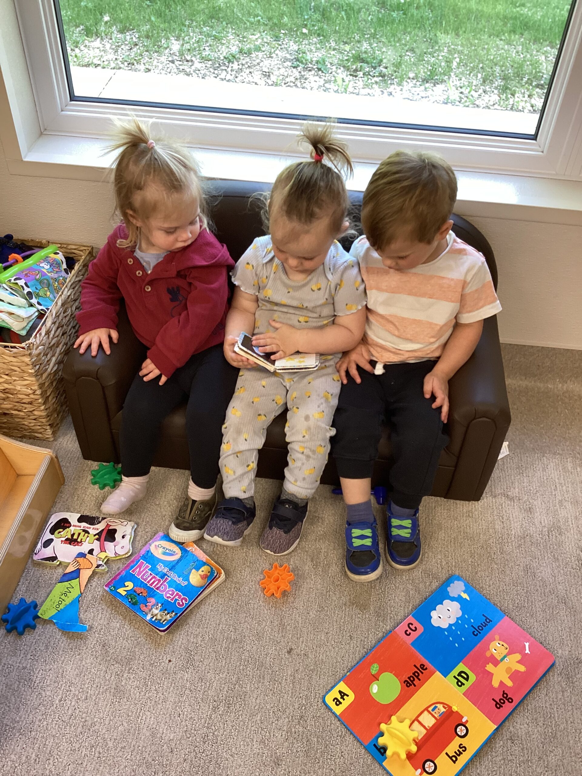 kids sitting on small kids sized couch playing with a toy